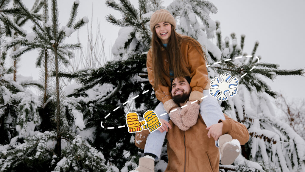 Eine Person sitzt auf den Schultern einer anderen Person vor dem Hintergrund schneebedeckter Tannenbäume.